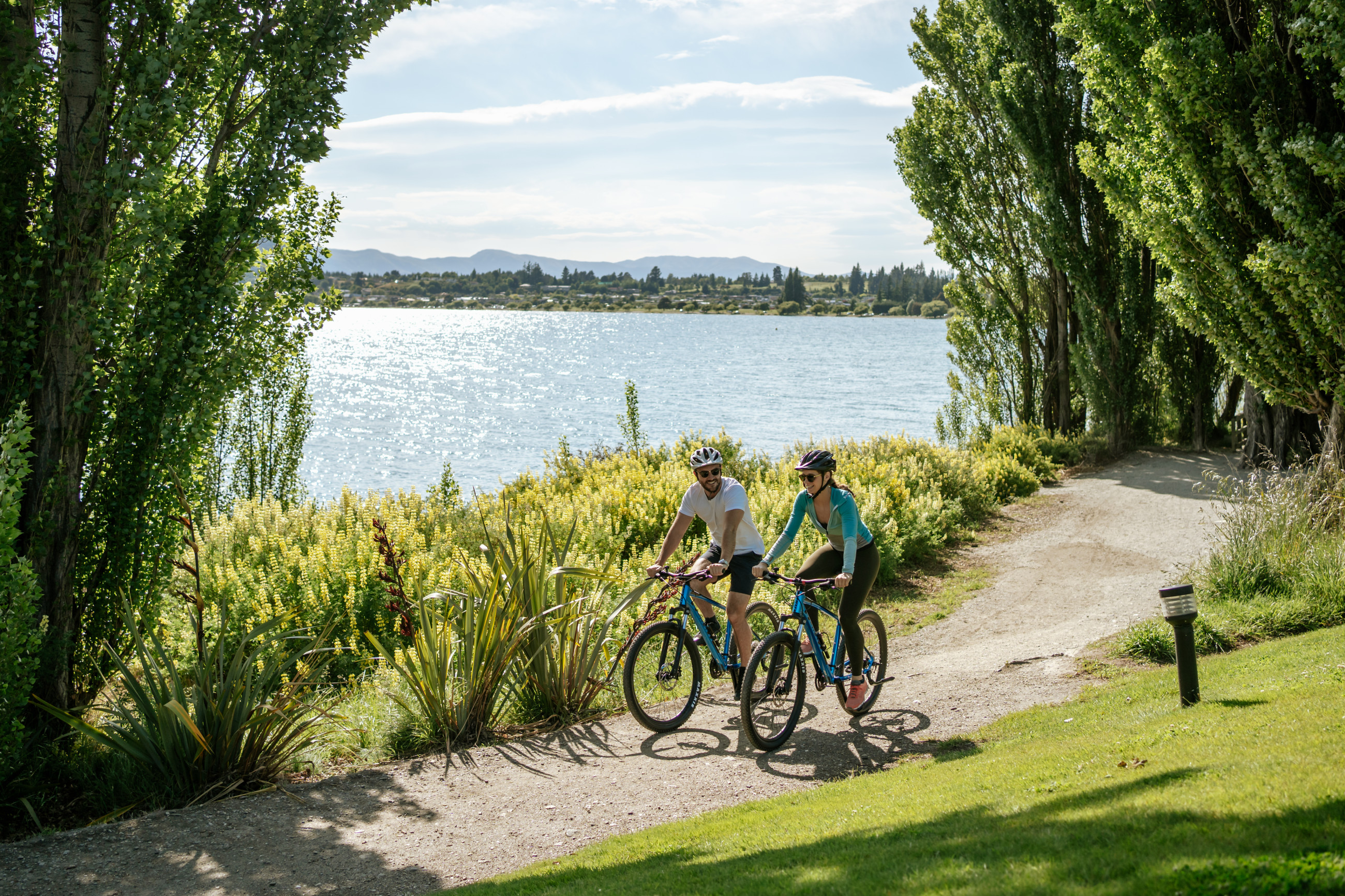 Two bikers outside Edgewater with Lake Wanaka behind them