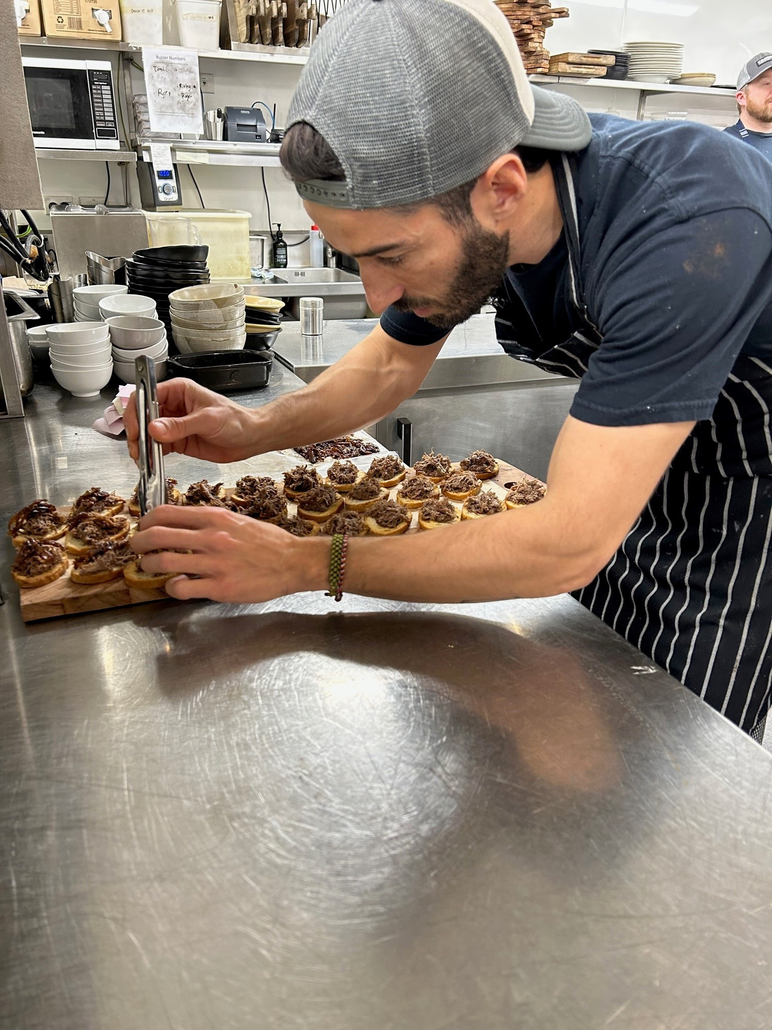 Chef placing pulled pork onto a platter of croutinis