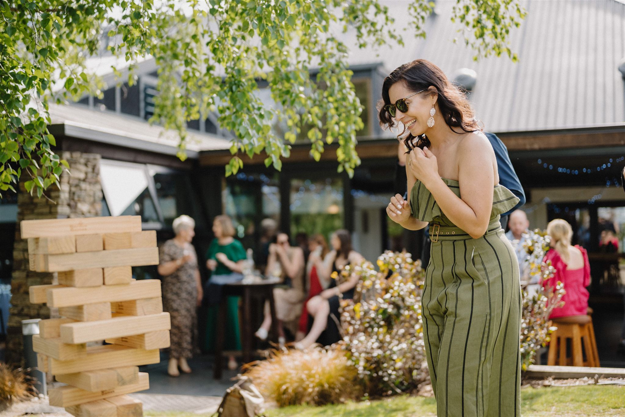 Girl alughing playing Jenga in front of the Edgewater Pavilion. People sitting on the patio in the background