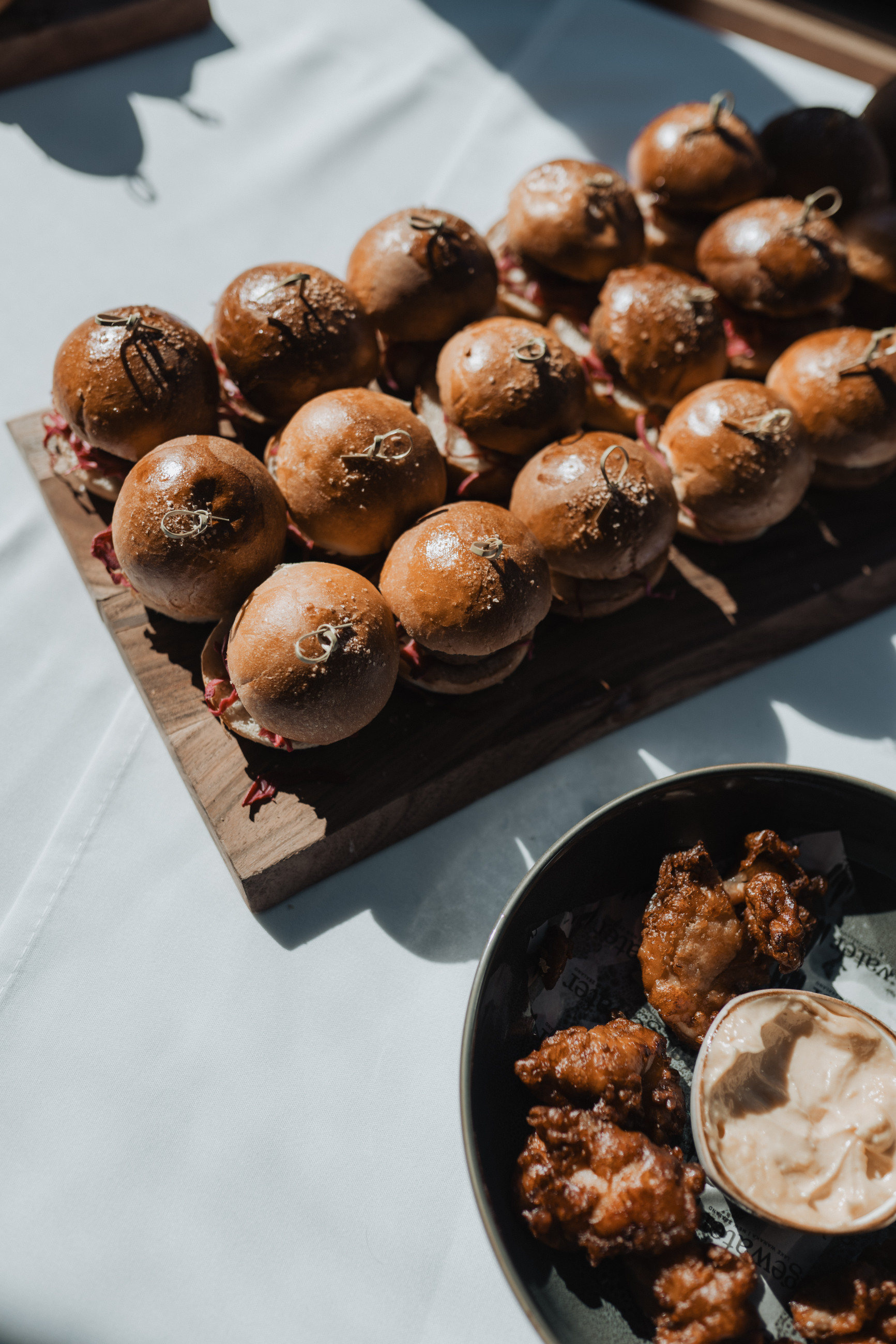 A Beef slider platter and karaage fried chicken platter on a white table cloth